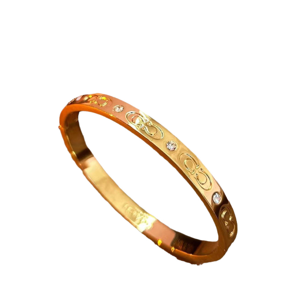 Close-up of Double C 3D engraved gold-plated open bracelet design