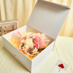 Side view of Bloom and Forever Eternal Glow Preserved Hydrangea Gift Box open on a cream surface, showing a pink and white preserved hydrangea bouquet inside a white luxury gift box, with an Especially for You greeting card beside it