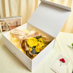 Side view of Bloom and Forever Eternal Glow Preserved Flower Gift Box Sunflower open on a cream surface, showing a yellow preserved sunflower bouquet with Love is Eternal ribbon inside a white luxury gift box, with an Especially for You greeting card beside it
