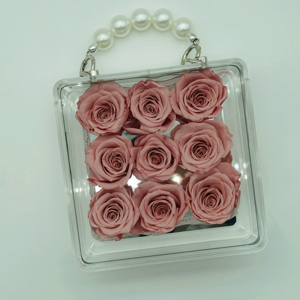 Close-up of petite eternal pink rose in acrylic handbag gift box