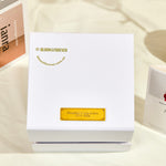 Top-down view of the closed white outer gift box for the Bloom and Forever Rotating Eternal Rose Jewelry Gift Box, showing the Bloom and Forever logo and bloomforever.com.au branding in gold with a personalised gold engraved plaque reading Thinking of you xoxox Love Asha, displayed on a cream surface with an Especially for You greeting card and magazine beside it